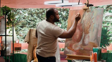 Bir sanat stüdyosunda, sanatçı bir palette çeşitli suluboya boyalar karıştırarak, tuvalde kırsal bir başyapıt yaratır. İnsan aletlerle resim yapar ve hünerini gösterir, sanat eserleri yaratır. Kamera A.