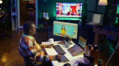 Yaratıcı Afro-Amerikan grafik tasarımcısı çift monitörlerde görüntüler düzenliyor, iyi organize edilmiş bir çalışma alanındaki dijital tasarım alanında yetenek ve adanmışlık sergiliyor. Kamera B.