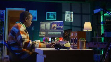 Kameraman evinde video klipleri ayarlıyor, görsel efektler eklemek için renk tekeriyle çalışıyor. Afro-Amerikan editör video sonrası prodüksiyon için fx montaj yapıyor. Kamera B.