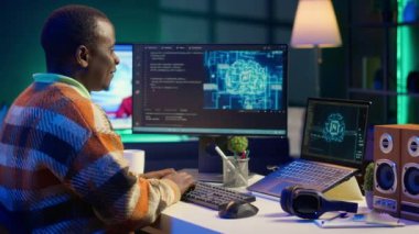 Programlama ve veri analizi için kişisel bilgisayar kullanan Afrika kökenli Amerikalı bir işçi. Evde çalışan erkek ağ uzmanı, bilgisayar üzerinde bilgi teknolojisi ve veri merkezini yönetiyor. Kamera A.
