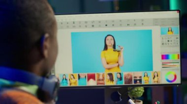 İyi organize edilmiş bir iş yerinde siyahi adam fotoğraf editörü gelişmiş yazılım araçları kullanarak çift ekran görüntülerini düzenliyor, yaratıcılık ve profesyonel özveri sergiliyor. Bilgisayar kurulumu. Kamera A.