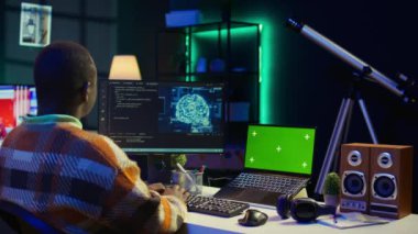 Afrika kökenli Amerikalı bir adam yapay zeka kullanarak bilgisayar üzerinde kroma anahtarı olan bir yazılım sistemi geliştiriyor. Erkek bilişim programcısı kodlama, siber güvenlik ve makine öğrenme yeteneğini gösteriyor. Kamera B.