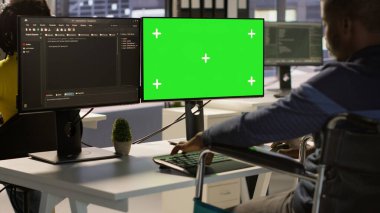 Tekerlekli sandalyede oturan engelli müteahhit yeşil ekran bilgisayarda başvuru sorunlarını düzeltiyor. Felçli bir adam şirket yazılımını modelleme bilgisayarı ve kamera A ile optimize ediyor.