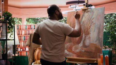 Afrika kökenli Amerikalı sanatçı, sanat stüdyosunda yeni bir eser yaratmak için yeteneğini kullanıyor ve başyapıtı için yenilikçi resim tekniğini kullanıyor. Genç çağdaş ressam bir sanat eseri üzerinde çalışıyor. Kamera B.