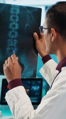Dikey Video Hintli sağlık uzmanı bir hastayla tıbbi uzmanlığını paylaşıyor, doğru tedavi ve iyileşme üzerine odaklanmak için x ışını taramalarını ve MRI teşhislerini gözden geçiriyor. Sigorta.