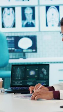 Dikey Video Hintli pratisyen hekim hastane kayıtlarını ve röntgen sonuçlarını inceleyip bir hastaya teşhis koyuyor. Sıhhiye taramaları ve sağlık raporları, profesyonel uzmanlık