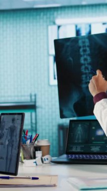 Dikey Video Doktoru, kabinesinde çalışan hasta bir hastaya teşhis raporu sağlamak için x ışını görüntüleme test bulgularını değerlendiriyor. Sağlık hizmetleri sağlayıcısı tedaviyi garantiliyor