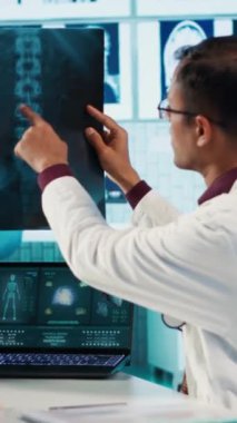 Dikey Video Hintli sağlık uzmanı bir hastayla tıbbi uzmanlığını paylaşıyor, doğru tedavi ve iyileşme üzerine odaklanmak için x ışını taramalarını ve MRI teşhislerini gözden geçiriyor. Sigorta.