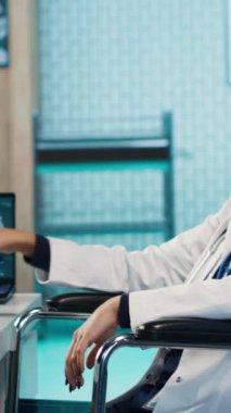 Dikey Video Hintli engelli kadın doktor hastasına danışmanlık yapıyor, hastanede tedavi ve iyileşme planı öneriyor. Genç bir adamla pratisyen hekim toplantısı. Kamera A.