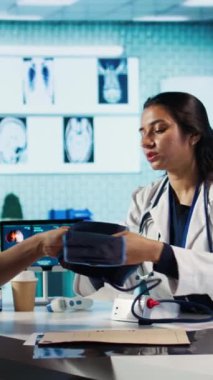 Dikey Görüntü Hekimi kan basıncı monitörüyle tıbbi konsültasyon yapıyor, nabız ve kalp atışlarını ölçüyor. Yüksek kalite kontrol ve sağlık hizmetleri sağlanması