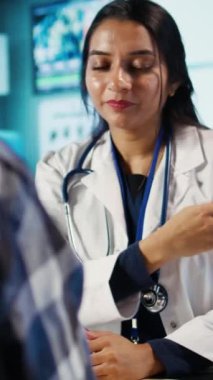 Hintli bir uzmanla tıbbi bir muayenehanede dikey video Optimetri danışmanlığı. Profesyonel optometrist göz muayenesi sağlar, görme ve tartışma için optik araçlar ve göz muayenesi kullanır