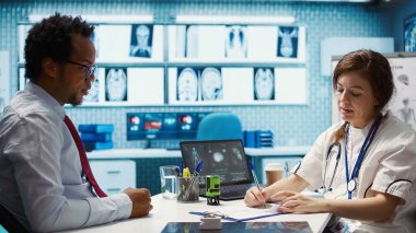 Tıbbi tedavi olarak antibiyotik ve vitamin öneren bir reçeteli belgeye damgasını basan pratisyen doktor. Doktor dolaba ilaç yazıyor. Kamera B.