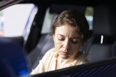 Kadın test sürüşü yapıyor, yatırım yapmadan önce arabayı inceliyor, kompartımanları keşfediyor. Müşteri sürücüsü, her şeyin düzgün çalıştığından emin olmak için düğmelere basıyor.