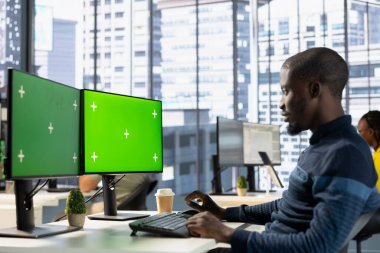 Ofis memuru Chroma Key PC monitörüne bakıyor, iş görüşlerini bulmak ve projeyi bitirmek için gerekli anahtar verileri kontrol ediyor. Yeşil ekran bilgisayarında veri analiz eden adam