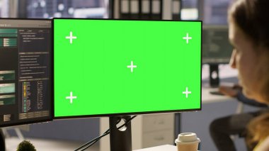 Bilgisayar bilimcisi çalışıyor, yazılım hata ayıklaması yapıyor. Model bilgisayar kullanarak, sorun giderme hataları yaparak. Ofisteki kadın yeşil ekran bilgisayarı kullanarak kodlama sorunlarını düzeltiyor, görevleri çözüyor, kamera A
