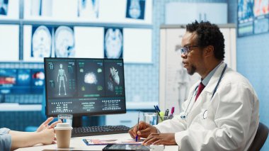 Kontrol ziyareti sırasında röntgen taraması yapan erkek hekim kabinedeki iyileşme tedavisini tartışıyor. Bir hastanın radyografi test sonuçlarını inceleyen bir doktor. Kamera A.