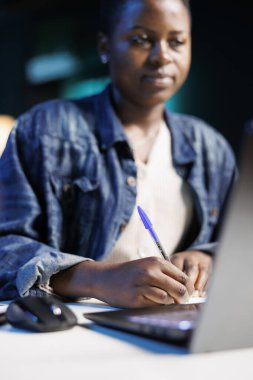 Evden çalışan, bilgisayarını kullanarak bilgi toplayan çok görevli bir Afro-Amerikan kadın. O, modern bir dairede masasında oturan genç bir yazar..