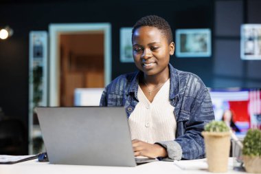 Masasında dizüstü bilgisayarıyla çalışan Afro-Amerikalı bir kadın. Kendini internete adamış ve internetten araştırma yapıyor. İnternette çalışmakla meşgul. Genç blogcu masada oturuyor ve kişisel bilgisayar kullanıyor.