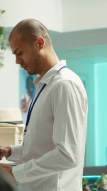 Dikey Video Ortadoğu perakende işçisi raflardaki yeni ürün koleksiyonunu düzenliyor, şık bir alışveriş merkezinde moda ürünleri düzenliyor. Tezgahtar detaylara dikkat ediyor. Kamera A.