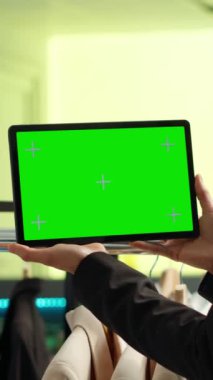 Dikey Videolu Asyalı kadın giyim mağazasında krom anahtar ekranlı moda sektöründe çalışan bir cihaz tutuyor. Müşterileri alışveriş merkezindeki butiğe çeken genç çalışanlar, moda ürünler.