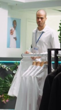 Dikey Video Ortadoğu mağazası çalışanı modern perakende mağazalarında kıyafet düzenliyor, moda tasarımcısından yeni koleksiyon için yer açıyor. Kaliteli bir alışveriş ortamı sağlıyorum. Kamera B.