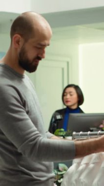 Dikey Video Modern Mağaza çalışanı müşteriye kıyafet seçeneklerini keşfetmede yardımcı oluyor, stil ve müşteri memnuniyetini sembolize ediyor. Moda uzmanlığını tartışan çeşitli adamlar. Kamera A.