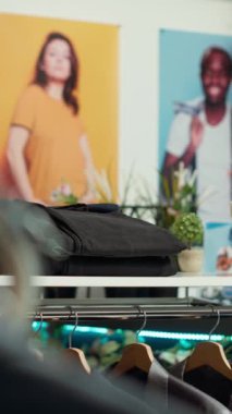 Bir tasarımcının modern giyim eşyalarının sergilendiği iyi organize edilmiş elbise rafları olan dikey Video Şık moda butiği. Günlük gömlekler, resmi spor ceketler, şık alışveriş deneyimleri sunan mağazalar..