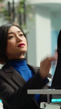 Dikey Video Perakende işçisi mankenler ve raflar üzerine modaya uygun yeni bir koleksiyon hazırlarken, Asyalı moda uzmanı ayrıntılara, kaliteli servise ve tarzdaki yeni eğilimlere dikkat çekiyor. Modern alışveriş