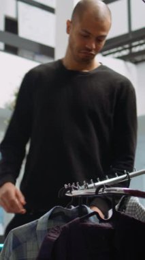 Dikey Videolu Ortadoğu müşterileri bir alışveriş merkezinde moda koleksiyonunu inceliyor, modaya uygun kıyafetleri ve canlı aksesuarları inceleyerek kişisel tarzını yükseltiyor. Modern seçici alışveriş