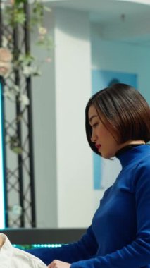Dikey Video Ortadoğu mağazası asistanı, bayan müşteriye canlı giysiler sunarak ve alışveriş deneyimini geliştirerek moda tavsiyesi sunuyor. Asyalı kadın perakende terapisi yapıyor.