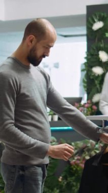 Dikey Video Alışveriş Merkezi çalışanı müşteriye yeni kıyafet koleksiyonundan seçmesi için yardım ediyor, kumaşın kalitesini ve potansiyel çeşitliliğini sunuyor. Güzel alışveriş deneyimi. Kamera B.