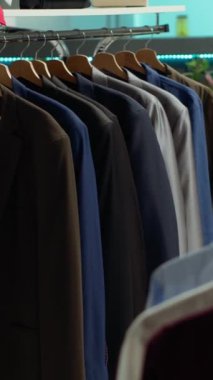 Boş bir mağazada klasik ve günlük giyim seçenekleriyle dolu dikey video mağazaları, çağdaş moda sergiliyor ve günlük tarzlarında zarafet arayan müşterilere çekici geliyor..
