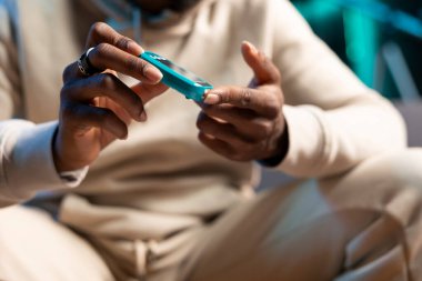 Kan oksijeni doygunluğunu ve kalp atışını takip etmek için insan tarafından kullanılan nabız oksimetresinin yakın çekim görüntüsü. Bulanık arka planda evde yıllık sağlık kontrolü yapan kişi tarafından kullanılan tıbbi ekipmanlara odaklan