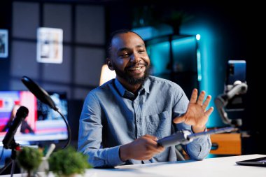 Stüdyodaki nüfuzlu kişi canlı yayın yapmak ve aboneleri selamlamak için selfie çubuğunda akıllı telefon kullanıyor. İnternet programı sunucusu cep telefonu kamerasıyla izleyicilerle ev turu yapıyor.