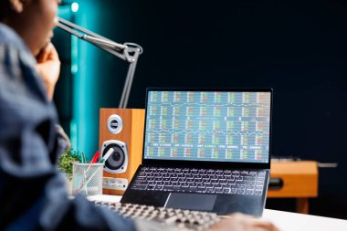 Evde dizüstü bilgisayarla çalışan siyahi kadın çevrimiçi ticaret yapıyor. Afrikalı Amerikalı kadın kişisel bilgisayarda finansal tabloları dikkatlice inceleyerek yatırım artışına olan bağlılığını gösteriyor..