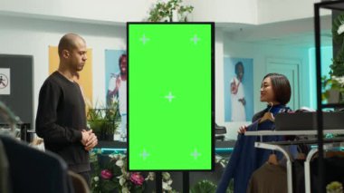 Kadın çalışan, mağazadaki erkek müşteriler için izole edilmiş bir modelin yanında kıyafet seçimi öneriyor. Moda tavsiyesi ve tüketim. Asyalı kadın alışverişte genç adama yardım ediyor..