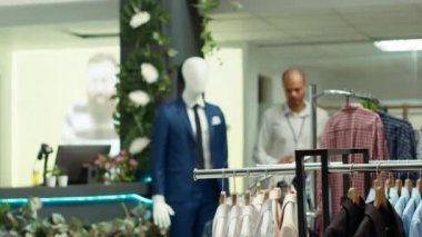 Tasarımcı butik asistanı raflarda canlı bir kıyafet seçimi düzenliyor, şık yeni koleksiyon kıyafetlerini ön plana çıkarıyor ve müşteriler için hoş bir alışveriş deneyimi yaratıyor. Kamera A.