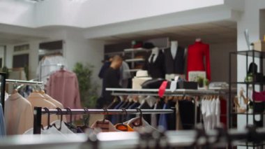 Moda butik işçisi, mağazadaki askıların iki parçasını ayırarak yeni koleksiyonla şık bir moda gösterisi hazırlıyor. Tasarımcıyı ayarlamak, ürünleri üretmek. Kamera B.