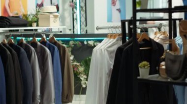 Alışveriş merkezi çalışanı raflarda yeni bir moda koleksiyonu organize ediyor, şehir perakende alanında moda kıyafetleri arayan müşteriler için bir görünüm kitabı konsepti sağlıyor. Modern alışveriş deneyimi. Kamera A.