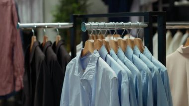 Raflara asılmış kıyafetlerle mağazada sergilenen modaya uygun moda butik ürünler, zamansız stil sunan şık gömlek ve ceket seçimleri sergileniyor. Boş lüks sergi salonu.