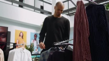 Orta Doğulu müşteri, moda koleksiyonunu bir alışveriş merkezinde keşfediyor. Moda kıyafetlerini ve canlı aksesuarlarını inceleyerek kişisel tarzını yükseltiyor. Modern seçici alışveriş. Kamera B.