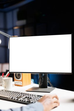 Serbest çalışan evde boş masaüstü ekran kullanarak oturuyor, bilgisayar ekranındaki beyaz şablona bakıyor. Masasında, Afrikalı Amerikalı müteahhit izole edilmiş boş bir monitör üzerinde çalışıyor..