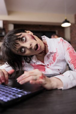 Exhausted woman at desk inputting data on laptop, being worked to death, close up shot. Businesswoman sending emails on notebook, covered in scars and turned into zombie, concept of capitalism issues clipart