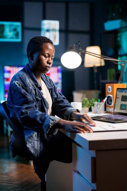 Adanmış Afrikalı Amerikalı kadın, dijital teknolojiyi çevrimiçi ticaret ve finansal analizler için kullanarak pazar büyüme eğilimlerini analiz ediyor. Evde çalışan serbest çalışan bir kadın, belgeleri gözden geçiriyor..