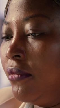 Dikey Video Siyah iş kadını masasında yorgunluk ve hüsrandan bitap düşmüş, aşırı yüklenmiş ve işyerinde rahatsız hissediyordu. Kadın lider endişe ve rahatsızlıkla baş eder.