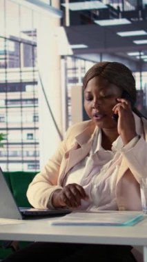 Dikey Video Afrikalı Amerikalı girişimci cep telefonuyla finansal planlama üzerinde çalışıyor, yatırımcılardan gelen bilgi ve görüşleri paylaşma çağrısına cevap veriyor. Kadın CEO telefon görüşmesinde iş yapıyor.