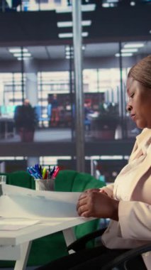 Vertical Video Yetkili Siyahi CEO 'su şehir merkezindeki üst düzey kurumsal ofiste çalışıyor, kurumsal bilgi grafiklerine odaklanıyor ve üretken bir hedef odaklı çalışma ortamını koruyor. Başarı hikayesi. Kamera.