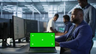 Çalışanlar, veri işleme gereksinimlerini optimize etmek için sunucu çiftliğinde çalışan yeşil ekran dizüstü bilgisayar kullanıyorlar. Masanın üzerindeki, veri merkezinde kodlama yapan işçilerin yanındaki, A kamerasının kapağını kapat.