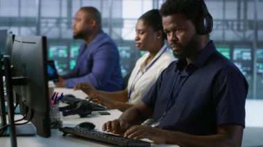 Klavyede veri merkezi yönetimi, donanımı yapılandırarak şirket ağ altyapısını koruyor. Sunucu merkezindeki Afrikalı Amerikalı işçi optimal sistem performansını garantiliyor, kamera A