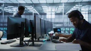 Sunucu odasındaki mühendis belgeleri inceliyor, felaket kurtarma planları geliştiriyor ve en az dinlenme süresini sağlıyor. Veri merkezinde kağıt okuyan işçiler, performansı izlemek için analitik kullanılarak, kamera A